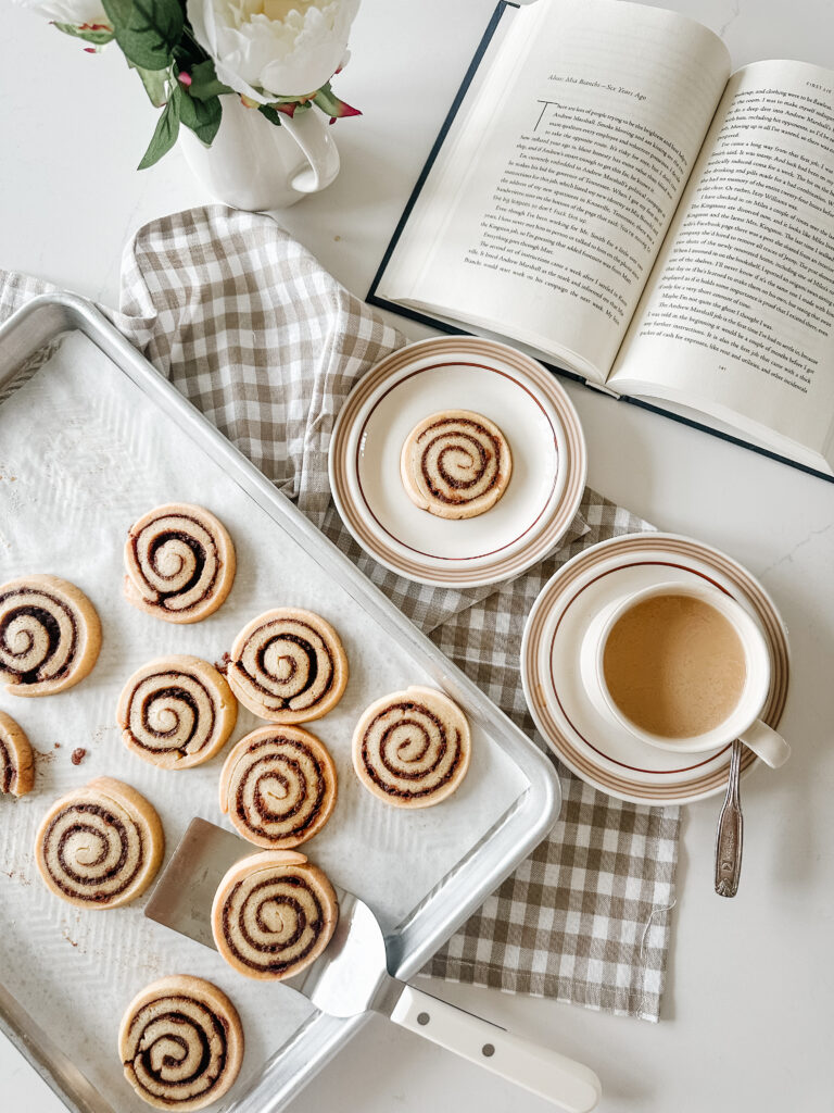 cinnamon roll cookies on a baking sheet with a cup of coffee